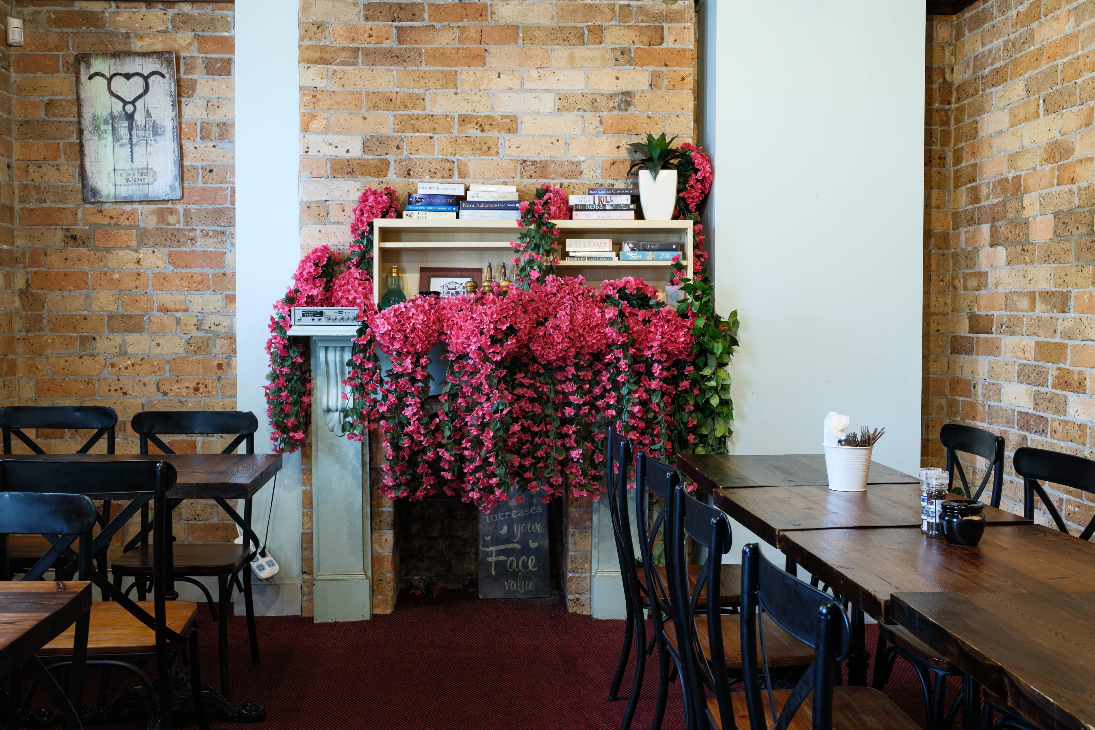 The cafe's private dining room — exposed brick, bistro chairs, and a fireplace dressed with a cascade of pink florals.